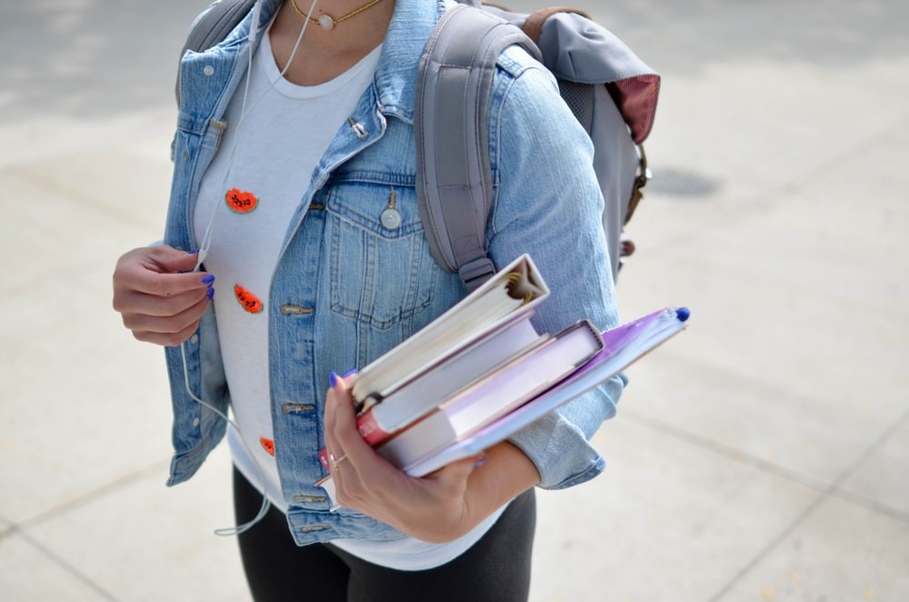Student heading back to school with many books in her hand.